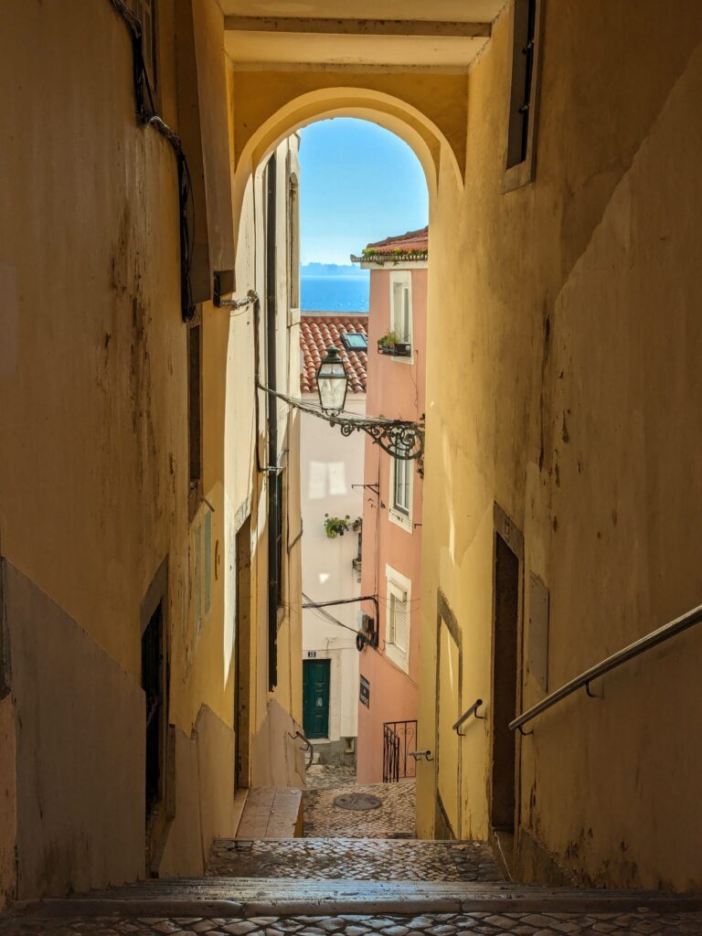 an alley way overlooking the sea in old town lisbon