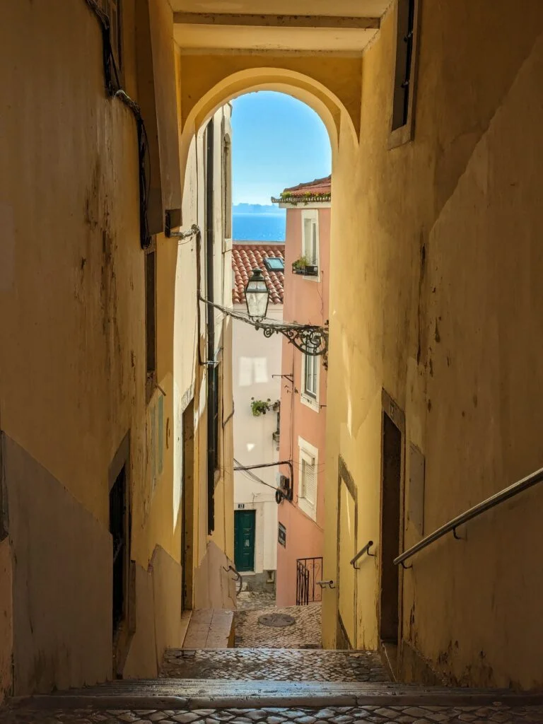 an alley way overlooking the sea in old town lisbon