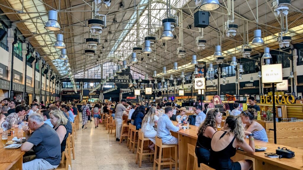 people sat at tables eating inside the time out market in lisbon