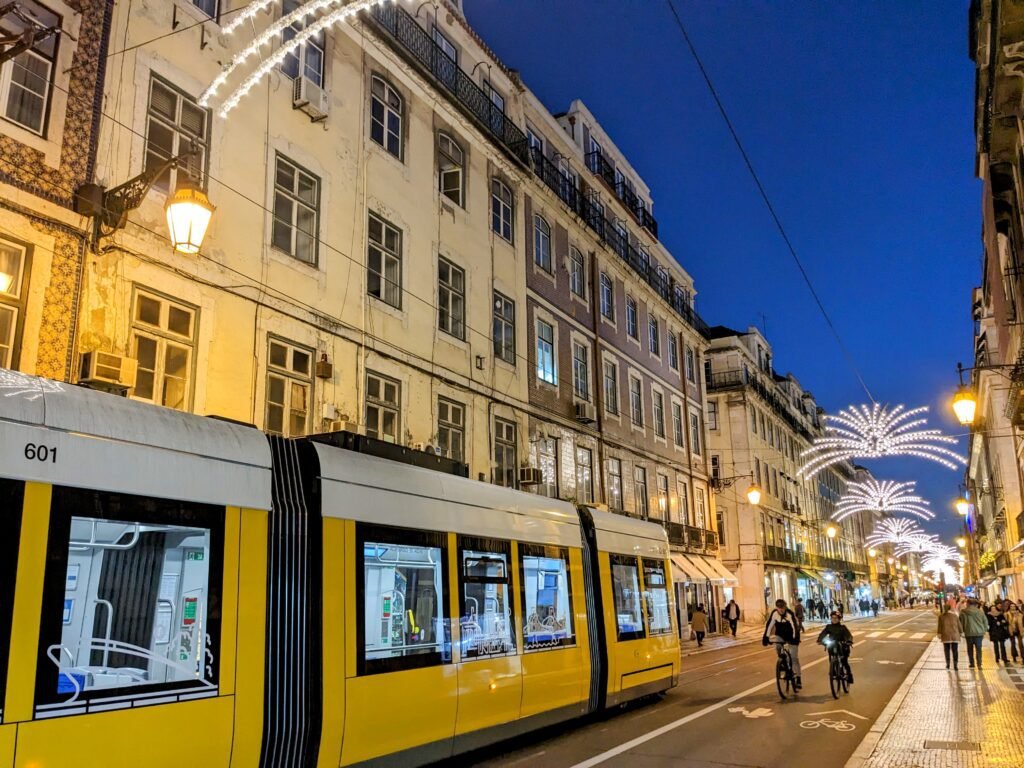 a yellow tram going past a street in baixa lisbon