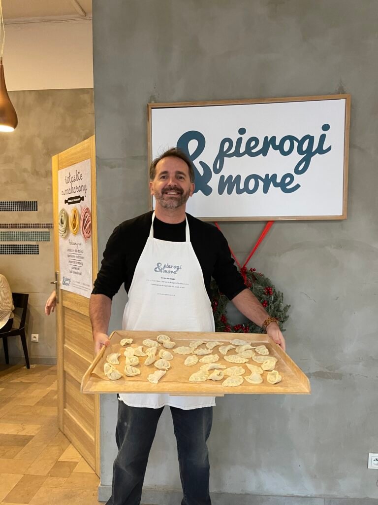 a man holding a large tray of pierogi dumplings in a cooking class in warsaw