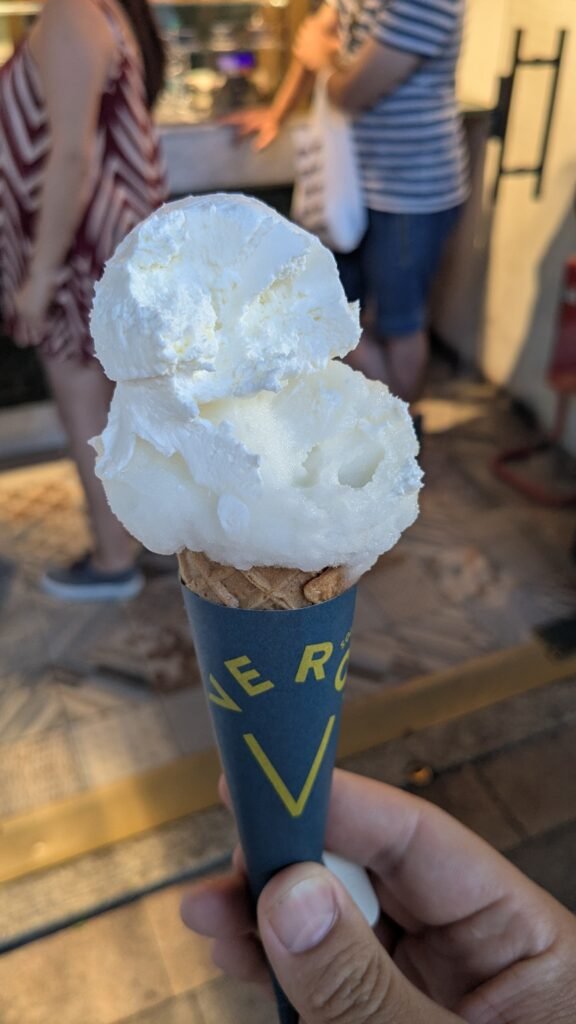 an italian gelato with two whites scoops in a cone